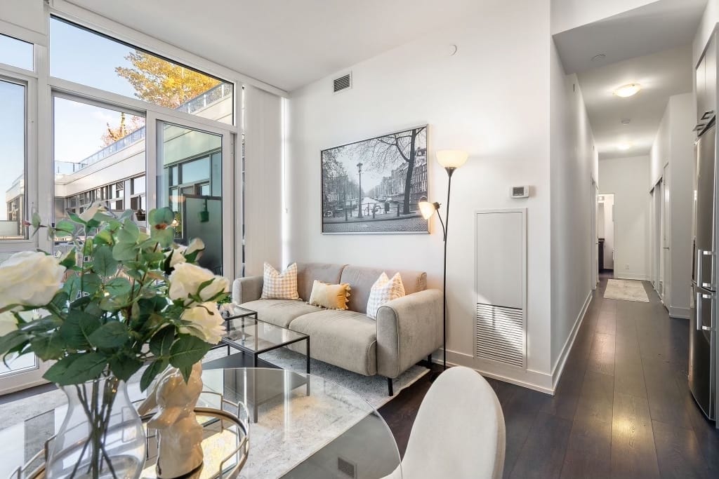 Fully Staged Living Room – Elegant Design with Accent Tables, Pillows, and Artwork – WeStage Canada Fully staged living room featuring elegant chairs, accent tables, decorative tray, fresh flowers, cozy pillows, art pictures, and stylish lamps.