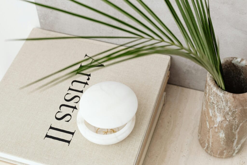 pexels-photo-6825477-6825477 Chic minimalist decor featuring a book, a leaf, and a marble vase for a stylish interior.